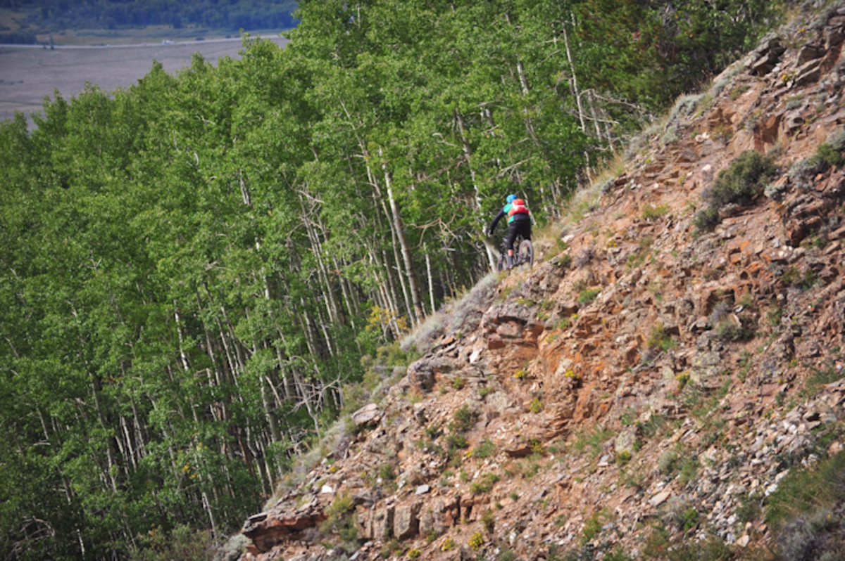 A rider carefully navigates a section of sharp rocks before diving into an aspen grove during stage 3 on the Roaring Judy trail.
