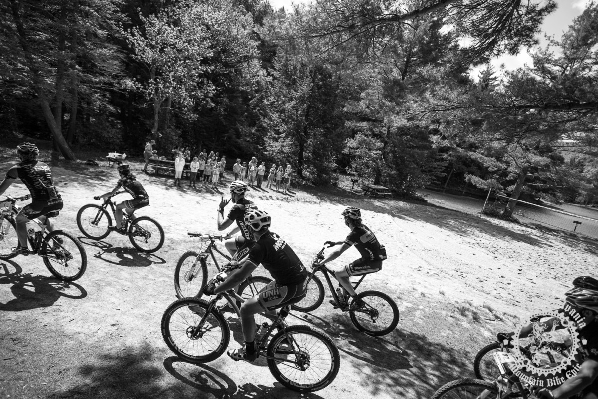 Riders roll past a group of elementary school students.