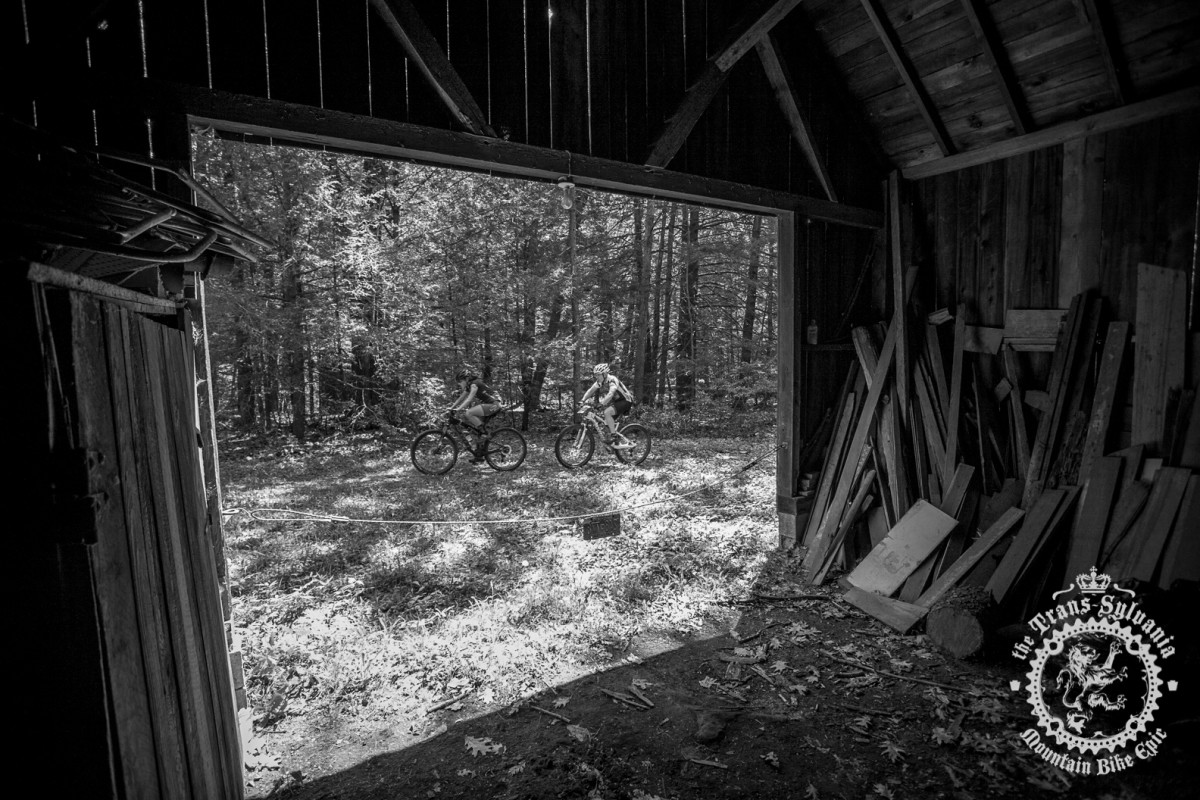 Riders pass by some abandoned buildings along the race course.