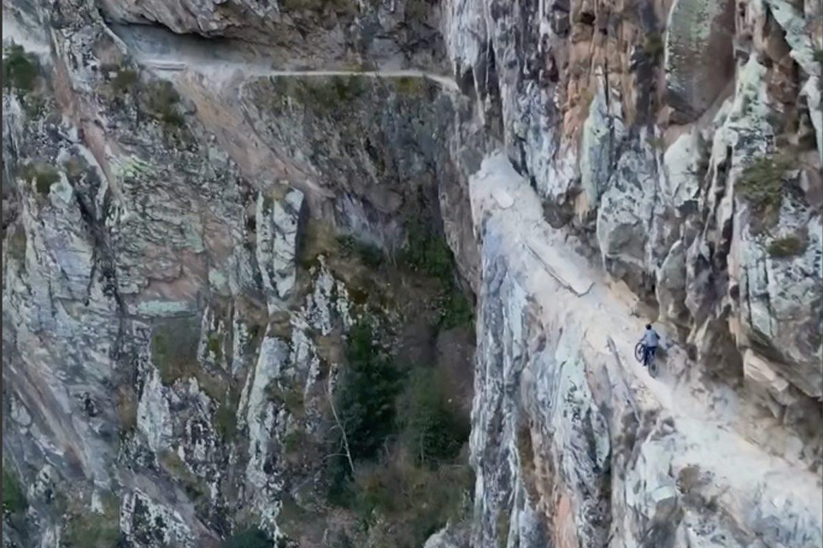 Kilian Bron Charges Along The Sheer Edge Of A Mountain